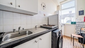 Keittiössä on pesuallas, liesi ja seinällä oleva kello.