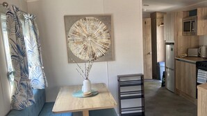 A compact living space with a kitchenette, a dining area with a bench, and a decorative piece on the wall.