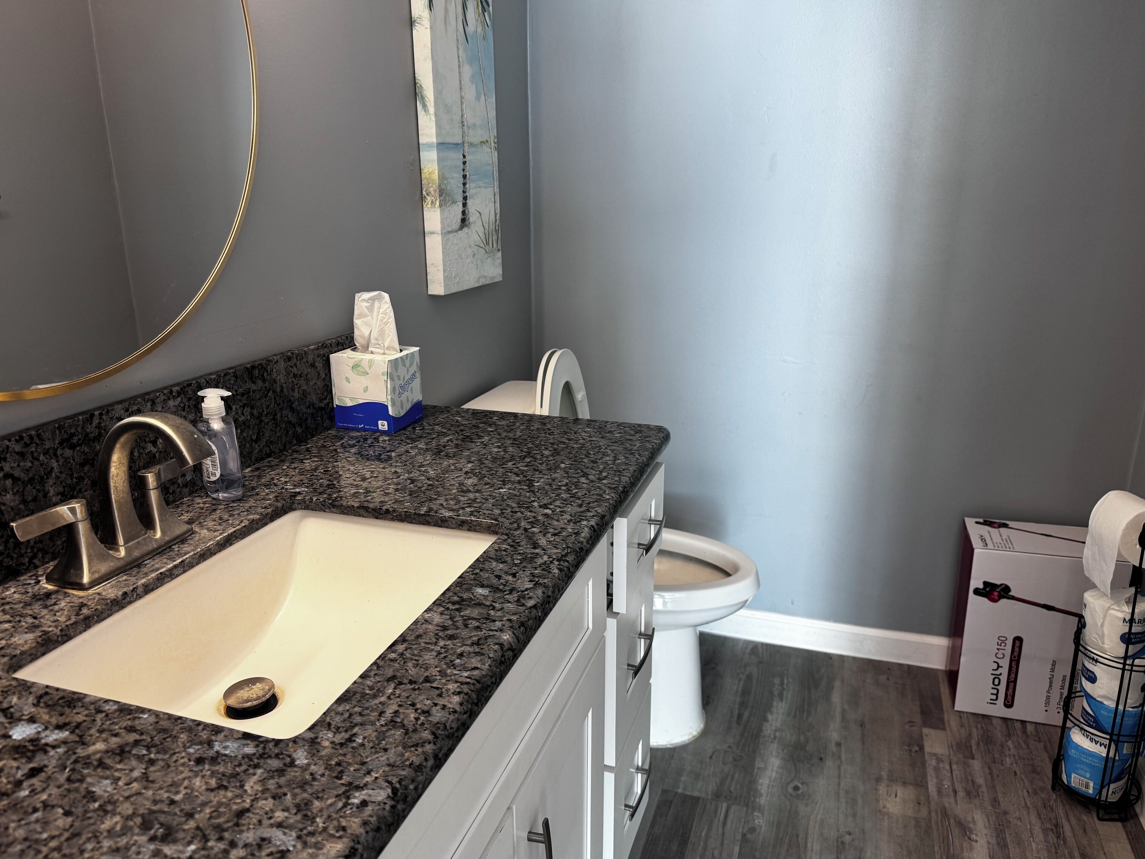 A bathroom with a granite countertop sink, a toilet, and a bidet.