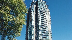 A tall building with a modern design, surrounded by trees and other buildings.