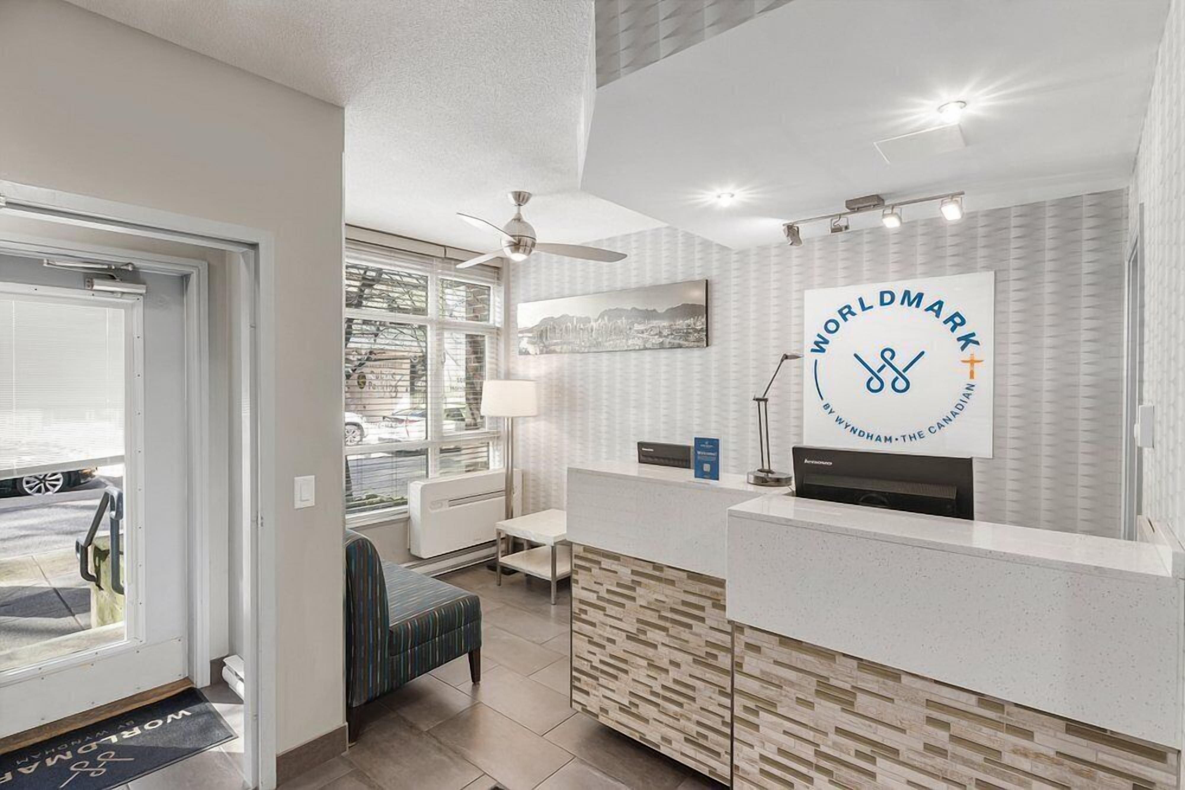 Ett välkomnande område med modern design, en stor logotyp på väggen och utsikt över omgivningarna genom stora fönster.