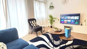 A living room with a sofa, a chair, a coffee table, a television, and a fireplace.