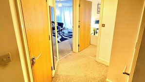A hallway with carpeted floors, wooden doors, and a ceiling light.
