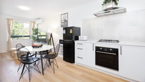 Una cocina moderna con comedor, que incluye un refrigerador negro, armarios blancos y una campana extractora de acero inoxidable.