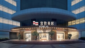 A modern hotel entrance with a curved facade, large glass windows, and a prominent sign.