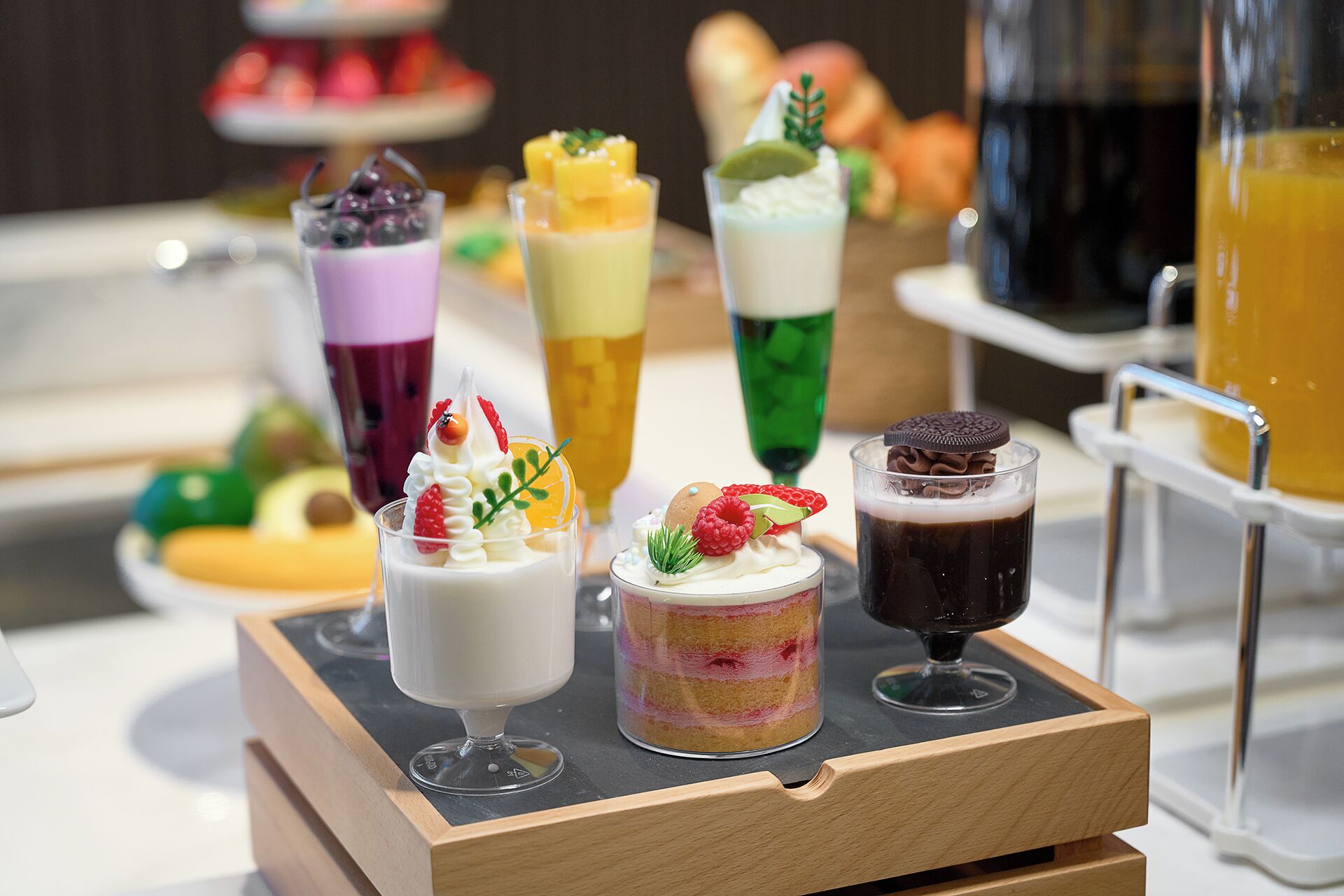A selection of desserts on a tray, including layered cakes and various fruit toppings.