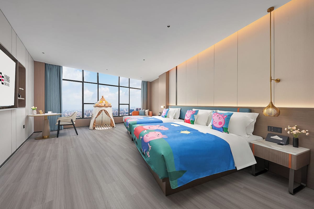 Una habitación de hotel con una cama grande, un escritorio, una silla, una pequeña tienda de campaña y vistas a la ciudad.