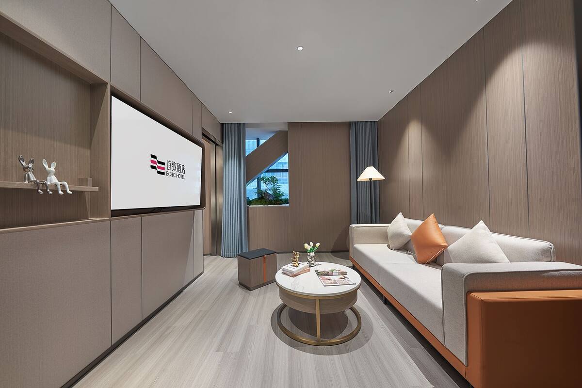 Habitación de hotel moderna con un sofá, una mesa de centro redonda y vistas al exterior.