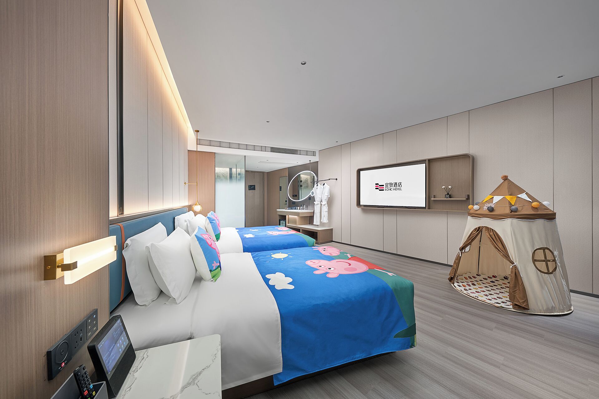 Habitación de hotel con dos camas, un televisor, un espejo, una pequeña tienda de juegos y una mesita de noche con un teléfono y un control remoto.