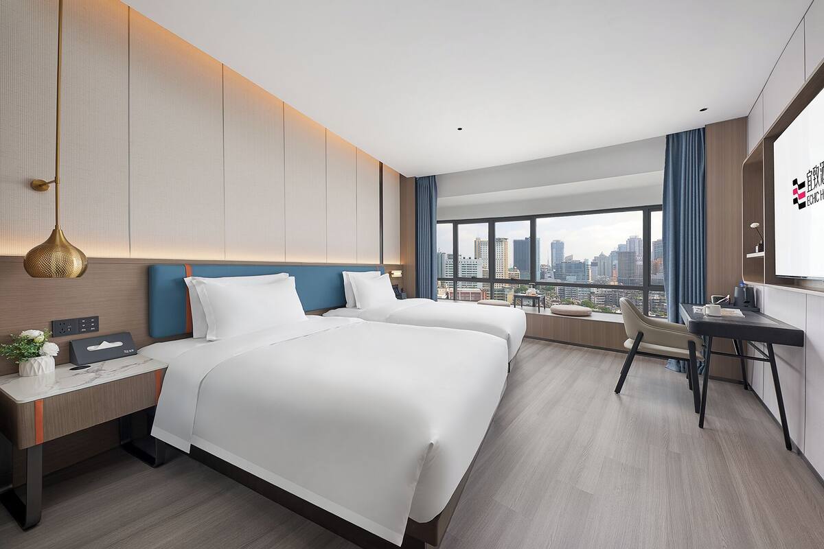 Una habitación de hotel moderna con una cama grande, un escritorio y vistas a la ciudad.