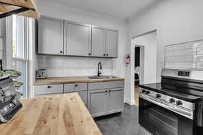 Eine moderne Küche mit weißen Schränken, einer Holz Arbeitsplatte, einem Edelstahlherd und einem Toaster.
