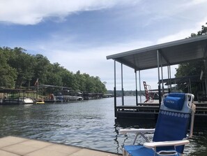 A boat docked at a marina with a covered seating area and a chair labeled 'NAUTICA'.