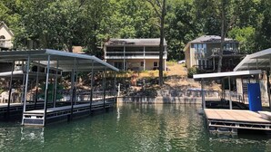 Una propiedad junto al lago con muelle, rampa cubierta para embarcaciones y una casa con balcón.