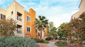 A residential building with a central courtyard, palm trees, and a pathway. - Las Vegas | Group Vegas Retreat | Pool + Strip | 2BR (Las Vegas)