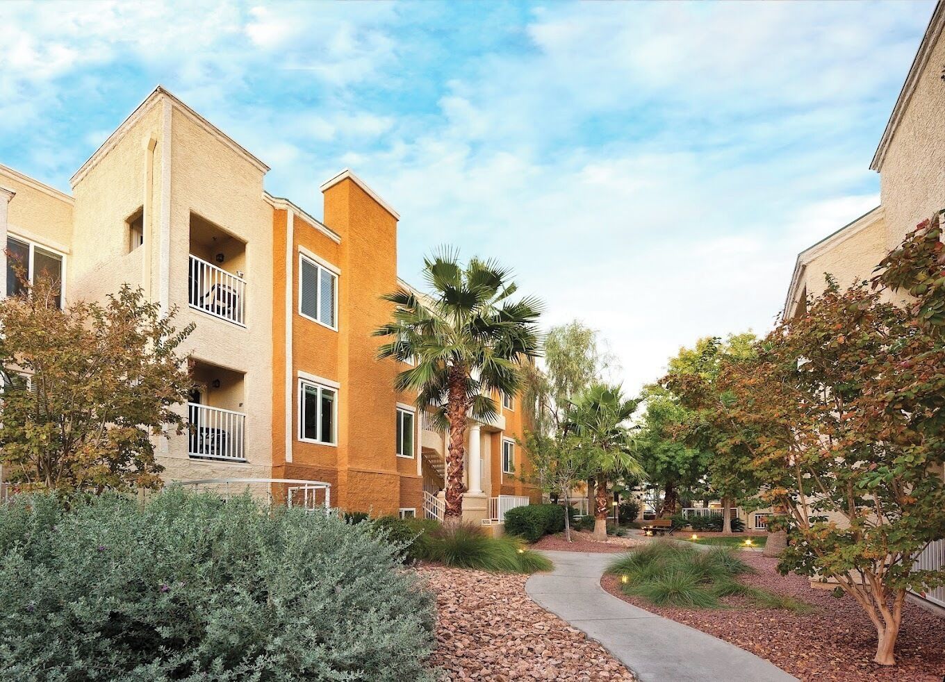 A residential building with a central courtyard, palm trees, and a pathway.
