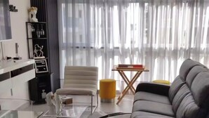 Ein modernes Wohnzimmer mit einer Couch, einem Couchtisch und einem Fernseher. Über dem Fernseher hängt ein Schild mit der Aufschrift 'Mi Casa SU Casa'.