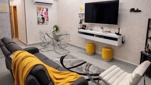 Ein modernes Wohnzimmer mit einer Couch, einem Fernseher, einem Couchtisch und einem Essbereich.
