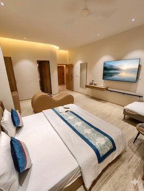 Une chambre d’hôtel moderne dotée d’un grand lit, d’une télévision à écran plat, d’un coin salon et offrant une vue sur un paysage boisé.