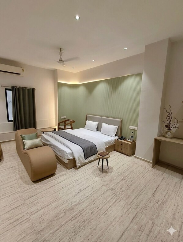 Una habitación de hotel moderna con una cama grande, un sofá, una mesita de noche y un escritorio.