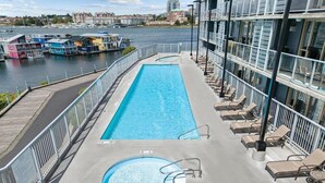 A swimming pool with a deck, lounge chairs, and a view of the water and buildings. - Victoria | Group Harbor Retreat | Pool + Harbor | 2BR (Victoria)