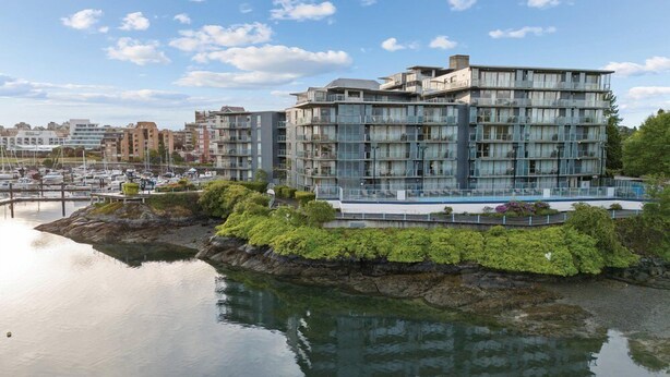 A modern multi-story building with balconies, situated by a calm body of water, likely a marina. - Victoria | Group Harbor Retreat | Pool + Harbor | 2BR (Victoria)