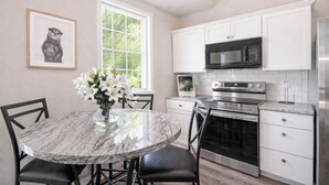A kitchen with white cabinets, a microwave, an oven, and a dining table with chairs. - Hidden Nature Haven - Stylish Comfort near Cincy (Park Hills)
