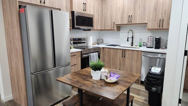 Una cucina moderna con elettrodomestici in acciaio inox, mobili in legno e un tavolo da pranzo in legno.
