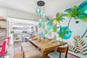 A dining area with a wooden table set for four, a bench, and a mural of palm trees on the wall. - Entire home in Clearwater, Florida, United States (Clearwater)