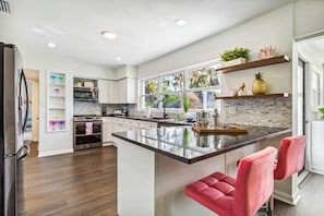 A modern kitchen with a central island, stainless steel appliances, and a view of the outdoors. - Entire home in Clearwater, Florida, United States (Clearwater)
