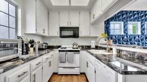 A kitchen with white cabinets, a black microwave, a stove, and a sink. - Luxurious & Cozy Loft ~ 5 Stars Location - King Bed - Private Patio Retreat (Los Angeles)