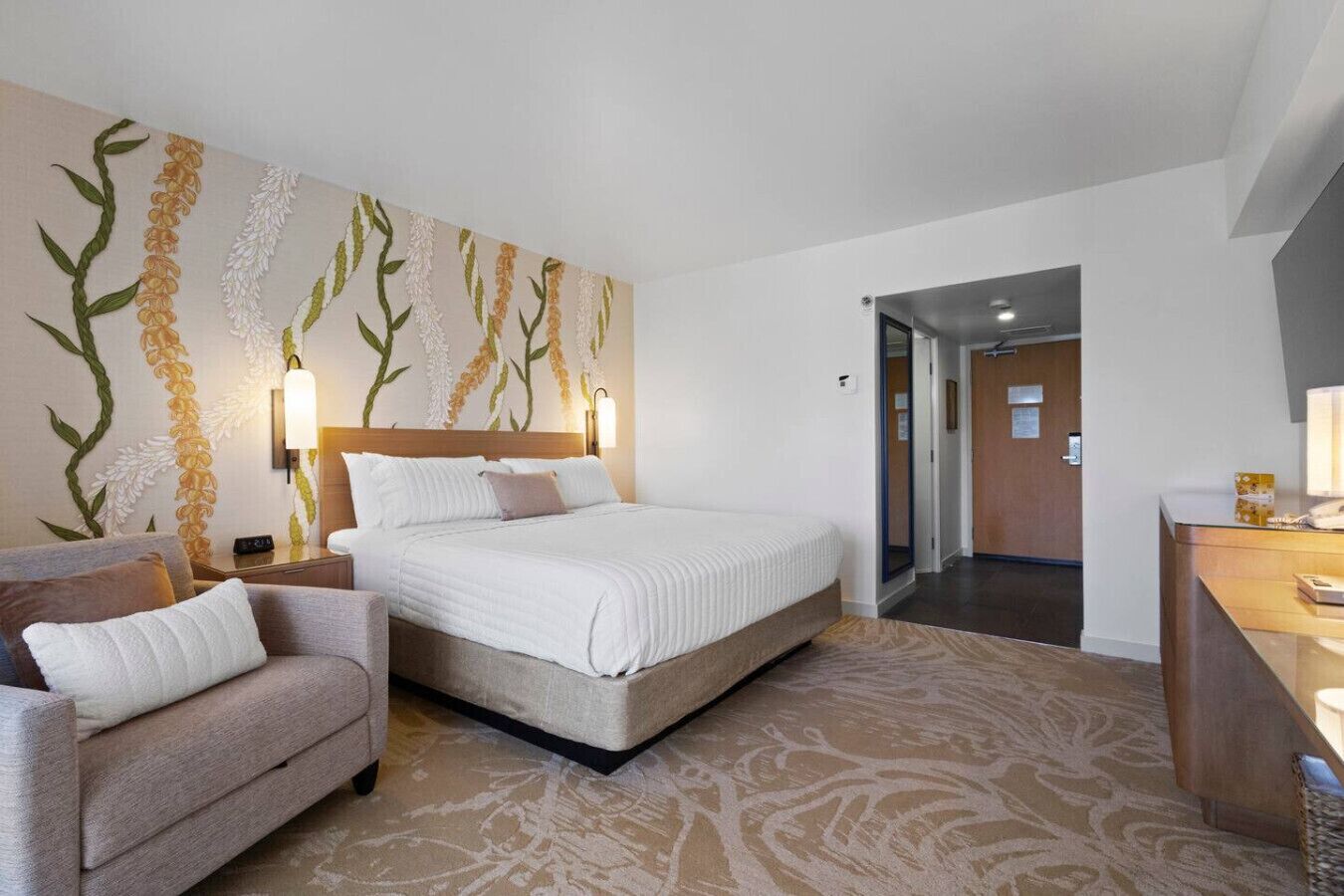 Une chambre d’hôtel équipée d’un lit, d’un bureau, d’une chaise et d’une grande fresque murale.