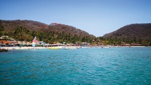 Una playa con barcos, sombrillas y cielo despejado.