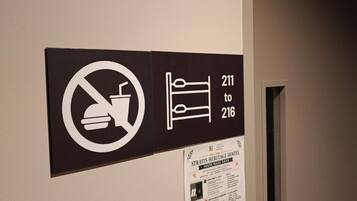 Un pasillo con un cartel que indica prohibido fumar y los números de habitación del 211 al 216.