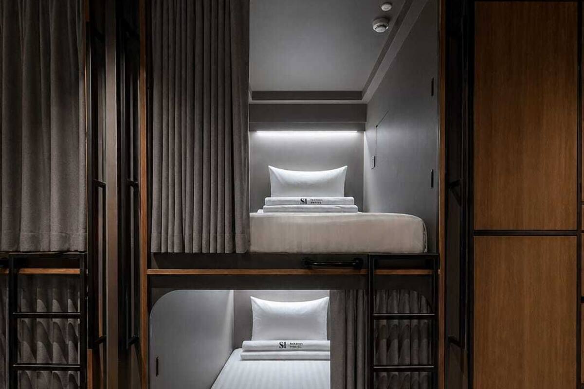 Un lit superposé avec une tête de lit, une étagère avec des serviettes pliées et une armoire en bois.