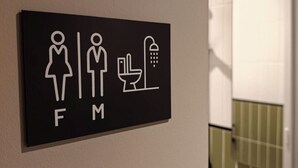 Kyltti, jossa on naisten ja miesten wc-tilojen symbolit, sekä käsienpesupiste.