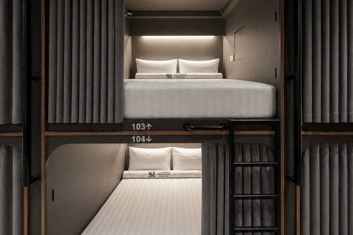 Une chambre avec un lit superposé, une tête de lit, une table de chevet et une étagère fixée au mur.