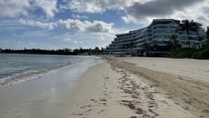 Een strand met een hotel op de achtergrond.