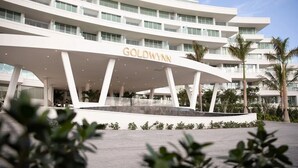 Een modern hotel met een opvallend 'GOLDWYN'-bord, een meerhoog gebouw en een aangelegde entree.