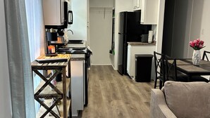 Una cocina moderna con armarios blancos, un refrigerador negro y una zona de comedor con una mesa y sillas.