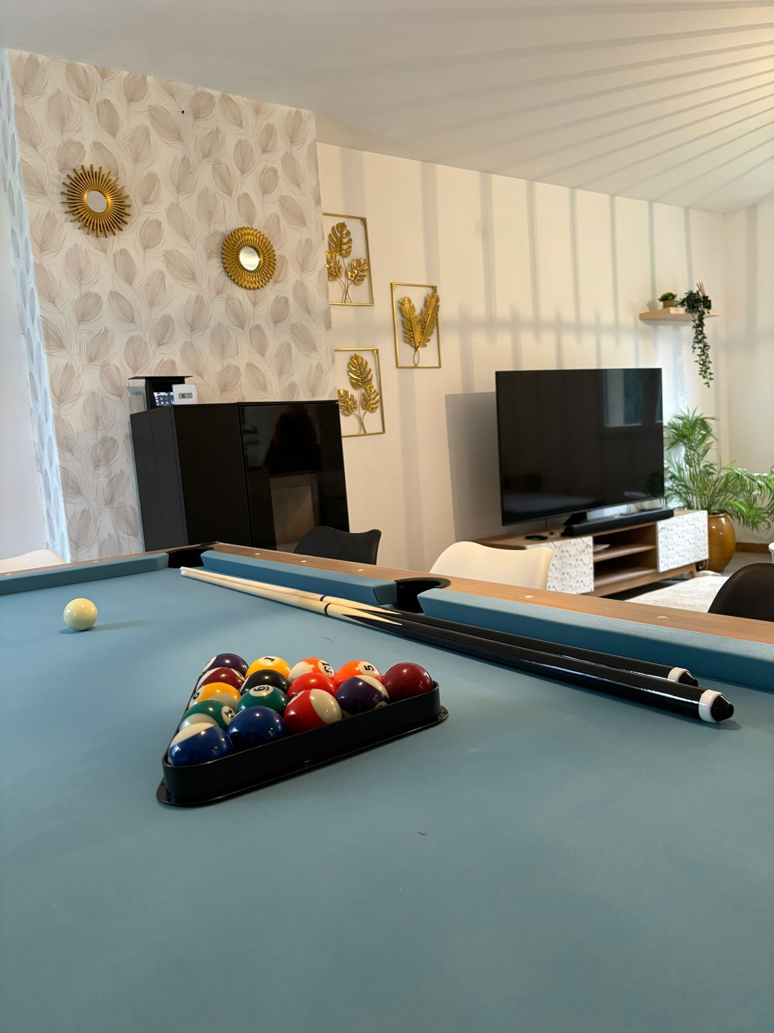 Una mesa de billar con bolas, un televisor y detalles decorativos en una sala de estar.