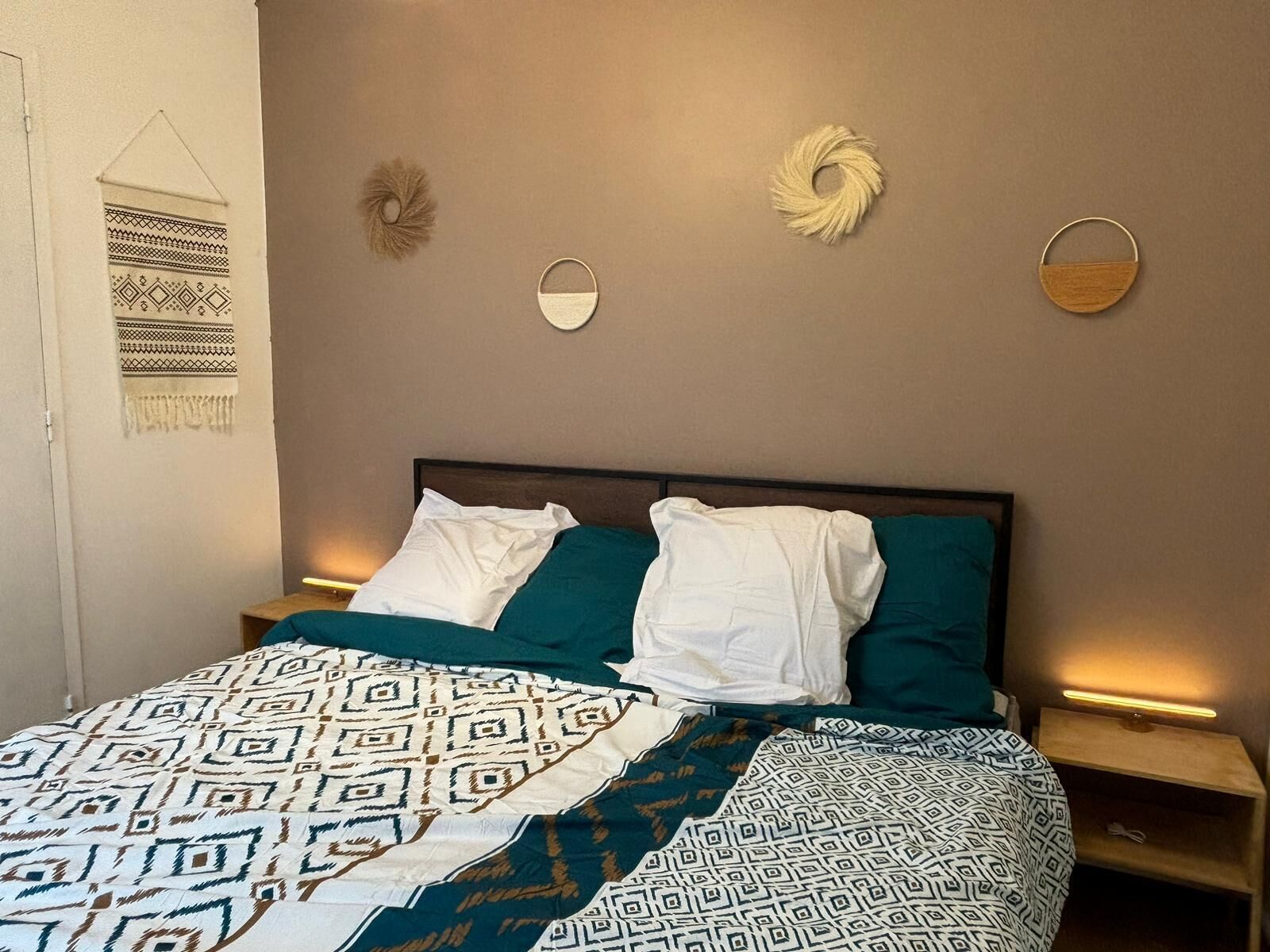 A bed with patterned bedding, a headboard, and bedside tables with lamps.