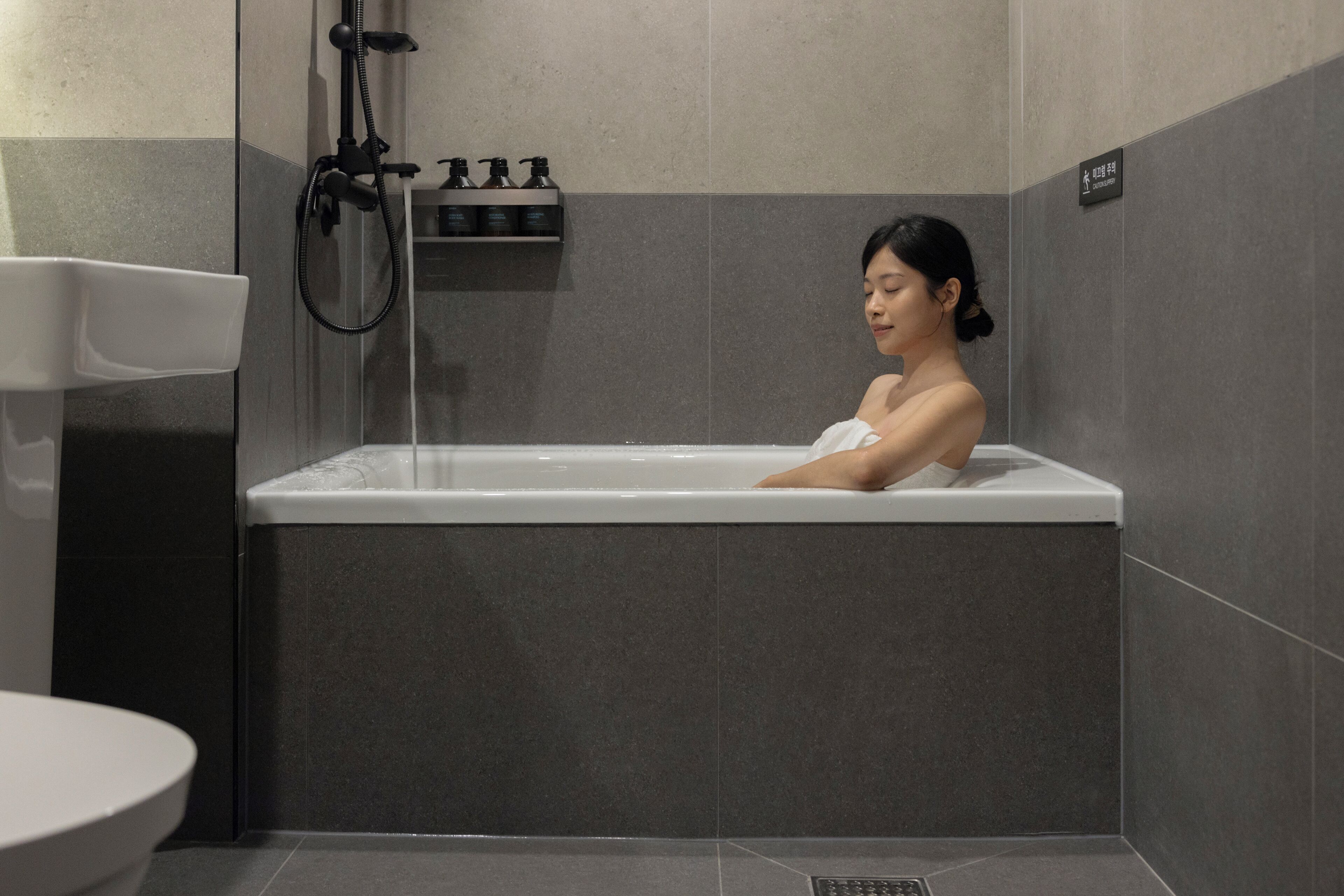 A modern bathroom with a bathtub, a toilet, and a showerhead.