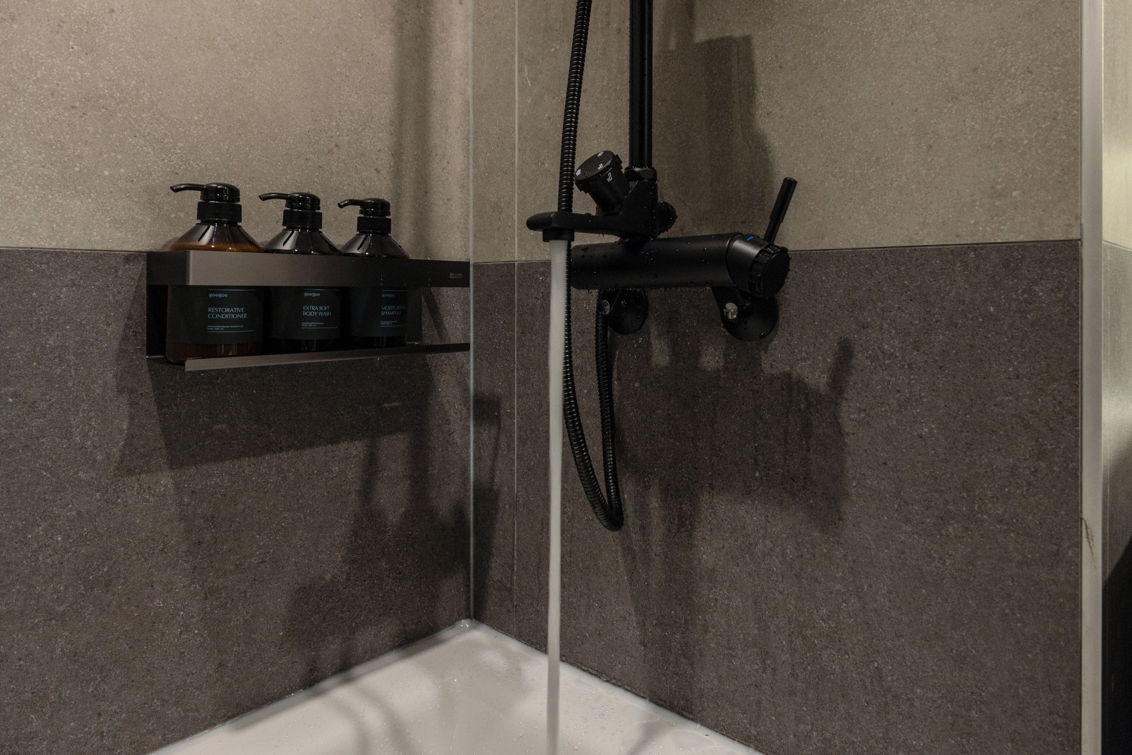 Un espace douche équipé d’un pommeau de douche à main et d’un robinet fixé au mur.