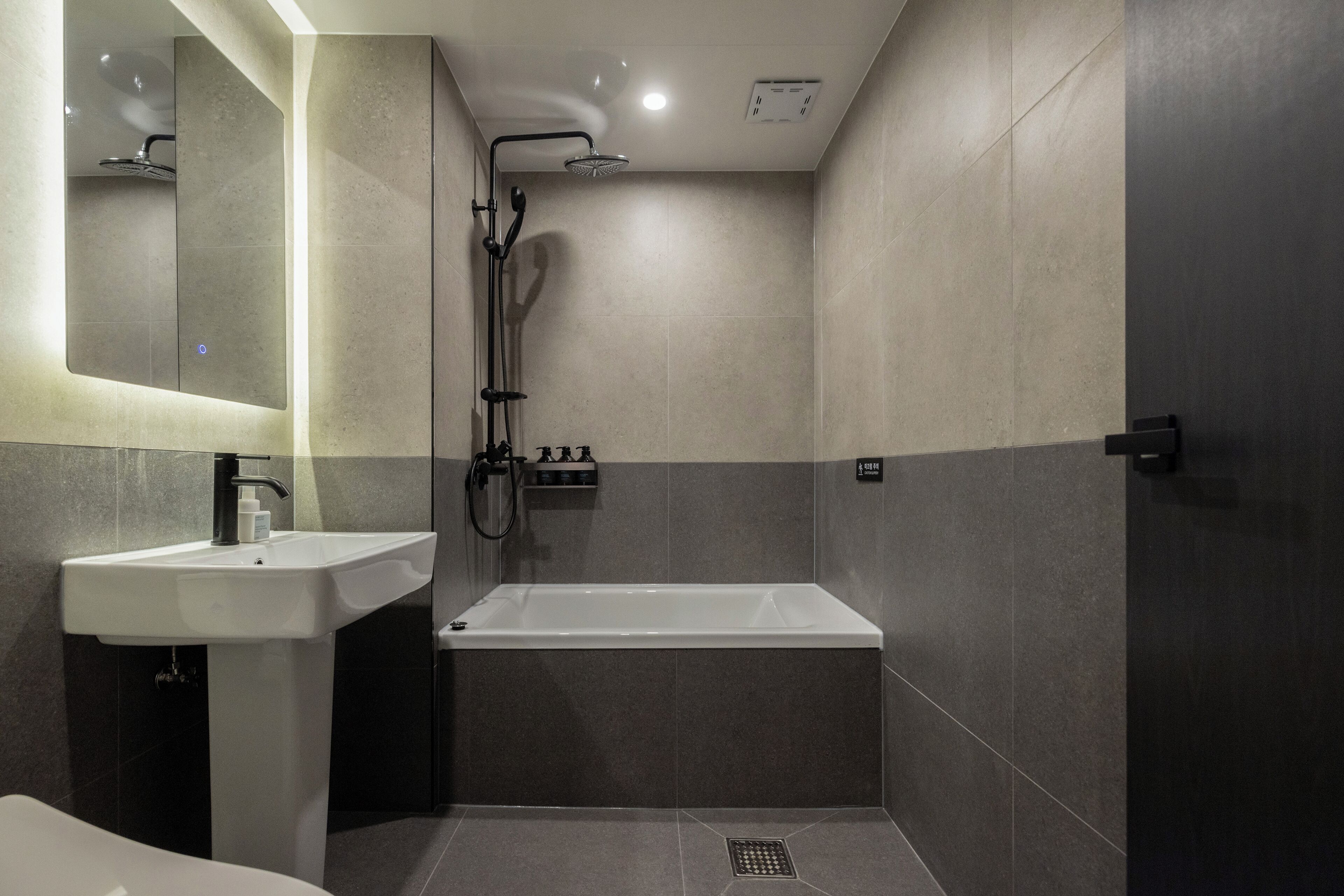 Un baño moderno con lavabo, espejo, ducha y bañera.