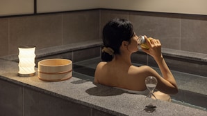 A person in a bathtub with a candle and a glass of water.