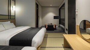 A hotel room with a bed, bedside table, and a small desk with a chair.