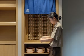 A person standing in front of a wooden shelf unit with multiple bowls. - Mitasuya Ryokan Hotel by Anook Gwangju (Gwangju)