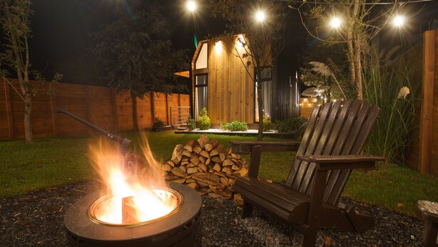 A backyard with a fire pit, a wooden bench, and a stack of firewood. - Cabin Box Huasca (HUASCA DE OCAMPO)