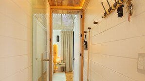 A narrow hallway with wooden flooring, a glass door on the left, and a wall-mounted hookboard on the right. - Cabin Box Huasca (HUASCA DE OCAMPO)