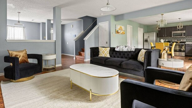Ein Wohnzimmer mit einem schwarzen Sofa, einem weißen Couchtisch und einer Treppe, die zu einer anderen Ebene führt.